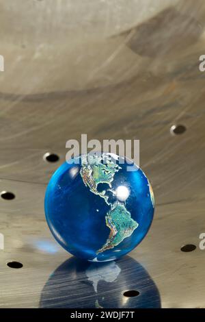 Ein Erdkugel-Marmor in einem Küchensieb aus Metall. Stockfoto