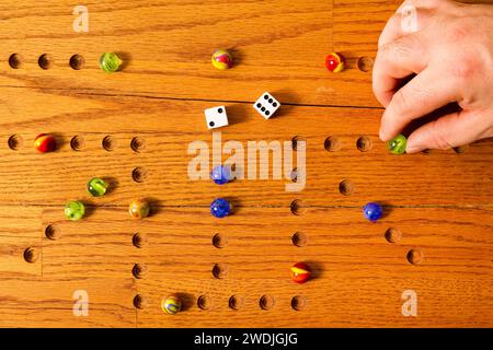 Eine Hand, die einen Marmor auf einem hölzernen Spielbrett bewegt. Stockfoto