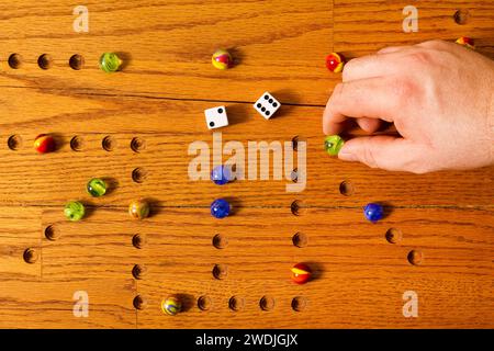 Eine Hand, die einen Marmor auf einem hölzernen Spielbrett bewegt. Stockfoto