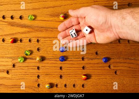 Eine Hand, die würfelt, bei einem Marmor-Brettspiel. Stockfoto