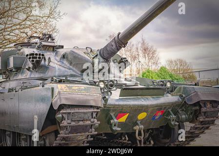 Ein Hauptschlachtpanzer des Chieftain in einem Luftmuseum. Die 120-mm-Kanone ist hoch und es gibt einen Himmel mit Wolke darüber. Stockfoto