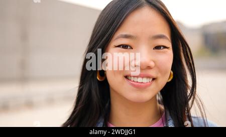 Asiatische junge Frau lächelt auf der Straße in die Kamera Stockfoto