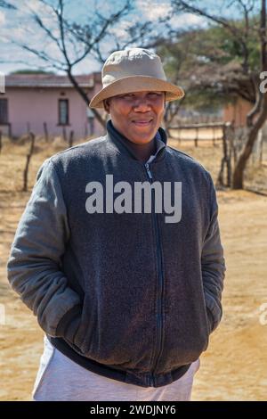 afrikanischer Dorfmann, der an einem sonnigen Tag im Hof steht Stockfoto