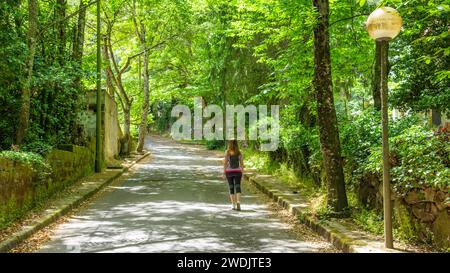 Mädchen, das im Wald von San Leonardo unter hohen grünen Bäumen läuft. Sardinien, Italien Stockfoto