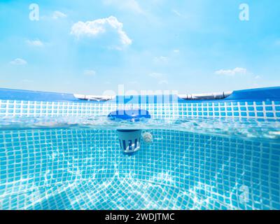 Geteilter Unterwasserblick eines Chlorwasserspenders in einem Pool unter blauem Himmel Stockfoto