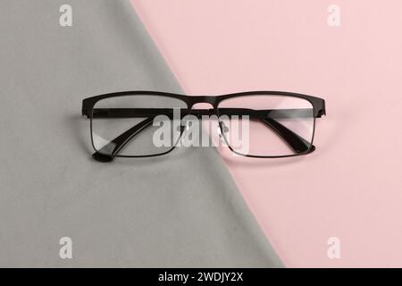 Glasreinigungsserviette aus grauem Tuch mit einem Paar Gläser darüber, Zusammensetzung isoliert auf rosa Hintergrund. Hochauflösendes Foto. Volle Schärfentiefe. Stockfoto