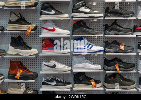 Schaufenster mit vielen Sportschuhen an der Wand. Schuhwand im Laden. Moderne neue, stylische Sneaker verschiedener Marken. Minsk, Weißrussland, 2024 Stockfoto