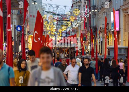 Türkische Fahnen mit nostalgischer Straßenbahn und Menschen in der Istiklal Avenue. Istanbul Turkiye - 10.28.2023 Stockfoto