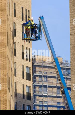 Scherenhub wird von Bauarbeitern für sicheren Zugang in der Höhe betätigt Stockfoto