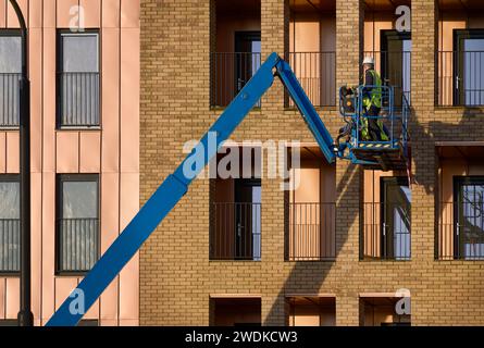 Scherenhub wird von Bauarbeitern für sicheren Zugang in der Höhe betätigt Stockfoto