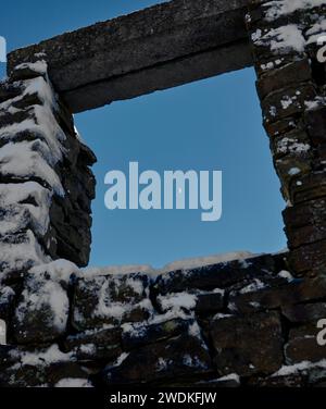 Ein bitterer Januarmond wird am Nachmittag nach einem plötzlichen Schneefall von einem Fensterrahmen in einem verlassenen Gebäude gehalten. Nidderdale. North Yorkshire Stockfoto