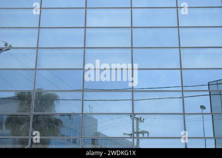 Verzerrtes Stadtbild spiegelt sich auf der Glasfassade eines modernen Gebäudes wider. Hintergrund abstrakter Fenster. Stockfoto