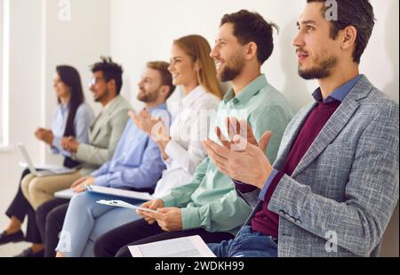 Junge Männer und Frauen applaudieren bei einer Geschäftskonferenz, einem Vortrag oder einem Seminar Stockfoto