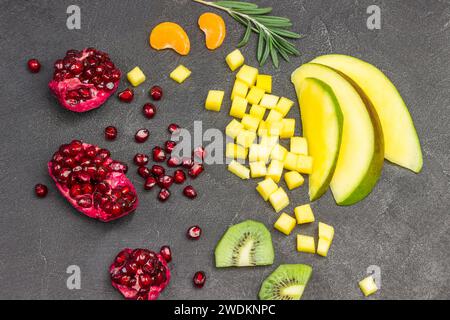 Stillleben von Mango, Granatapfel, Kiwis auf schwarzem Hintergrund. Flache Lagen. Gesunde Ernährung vegetarische Ernährung. Stockfoto