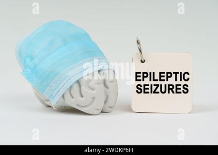 Medizinisches Konzept. Auf einer weißen Oberfläche neben dem Gehirn befindet sich ein Notizblock mit der Inschrift "epileptische Anfälle" Stockfoto