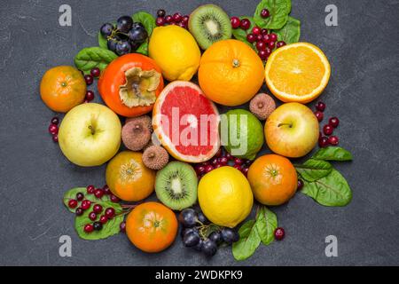 Verschiedene exotische Früchte in verschiedenen Farben. Mandarinen, Grapefruit, Litschi, Kiwi und Trauben mit Mangold-Blättern. Schwarzer Hintergrund. Flache Lagen Stockfoto