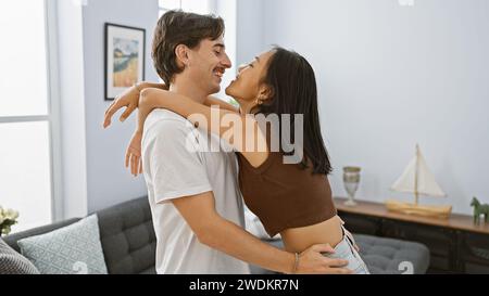 Interrassisches Paar, das glücklich in einem modernen Wohnzimmer umgeht und Liebe und Einheit in einem zeitgenössischen Ambiente vermittelt. Stockfoto