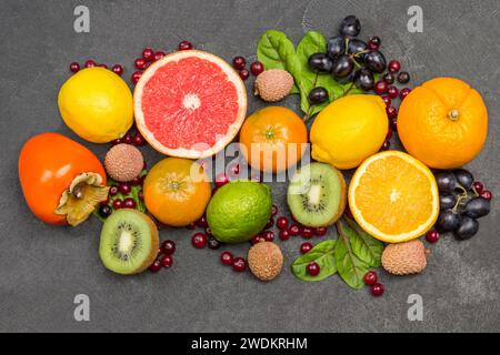 Verschiedene exotische Früchte in verschiedenen Farben. Mandarinen, Grapefruit, Litschi, Kiwi und Trauben mit Mangold-Blättern. Schwarzer Hintergrund. Flache Lagen Stockfoto