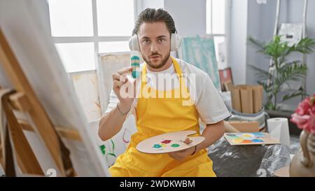 Junger hispanischer Künstler, der Videoanrufe mit Kopfhörern im Kunststudio hat Stockfoto