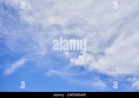 Eine ruhige Skyline mit flauschigem Kumulus und zerklüfteten Zirruswolken vor einem klaren blauen Hintergrund, die das Wesen eines ruhigen Tages einfangen. Stockfoto