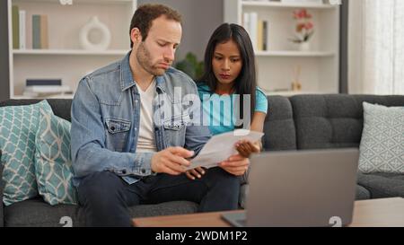 Wunderschönes Paar, das ein Notebook benutzt, um Dokumente zu lesen und zu Hause verärgert zu sein Stockfoto