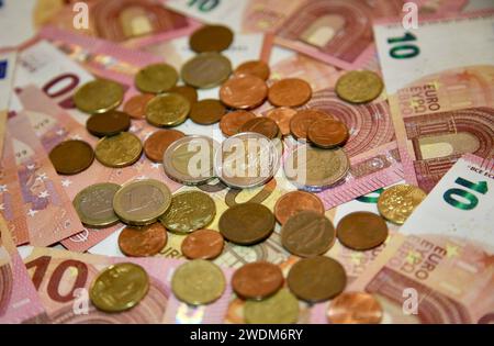 Eine Handvoll Kleingeld und ein Haufen Euro-Banknoten Stockfoto