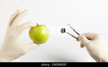 Zahnärztliche Versorgungskonzepte. Zahnarztwerkzeuge professionelle Ausrüstung und grüner Apfel auf weißem Hintergrund. Stockfoto