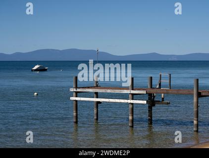 Pier am Lake Tahoe mit Boot und Bergen in der Ferne. Blauer Himmel, sonniger Tag. Stockfoto