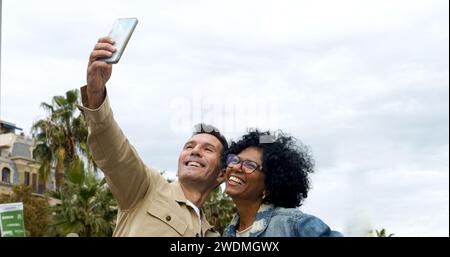 Ein vielseitiges Touristenpaar mittleren Alters macht ein Selfie in einer Stadt. Heterosexuelles Paar im Urlaub Stockfoto