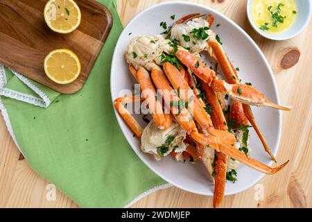 Gedämpfte Krabbenbeine mit Knoblauchbutter, Zitrone und Petersilienflocken Stockfoto