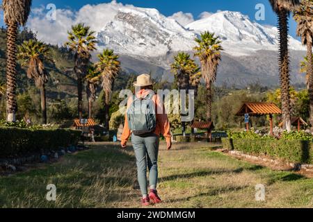 Touristenwanderungen durch die Stadt Yungay mit dem schneebedeckten Huascaran im Hintergrund. Stockfoto