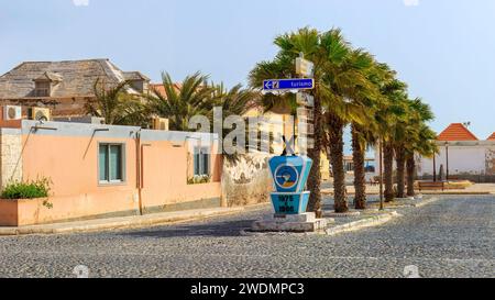 Die kopfsteingepflasterte Straße von Sal Rei, gesäumt von lebhaften Gebäuden und Palmen, lädt Touristen ein, den Charme von Boa Vista zu erkunden. Hochwertige Fotos Stockfoto