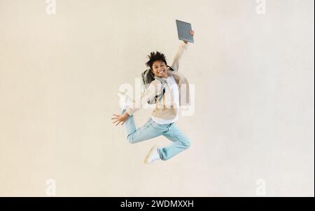 Sorgloser chinese mit Computer in der Hand, der hochspringt Stockfoto