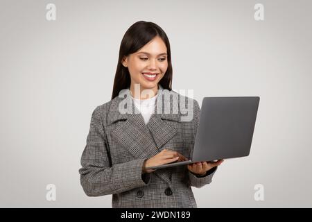 Lächelnde Geschäftsfrau mit Laptop, Technologie bei der Arbeit Stockfoto