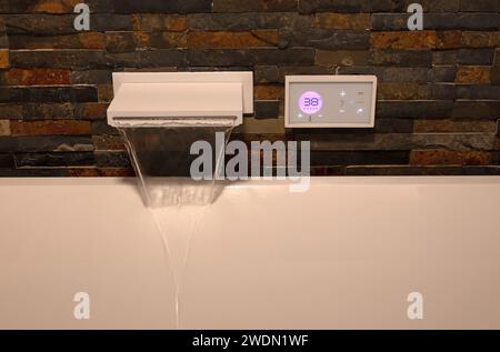 Moderner digitaler Wasserhahn, der das weiße Bad füllt, selektiver Fokus Stockfoto