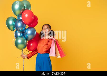 Schwarzes Teenager-Shopper-Mädchen mit hellen Ballons und Taschen, Studio Stockfoto