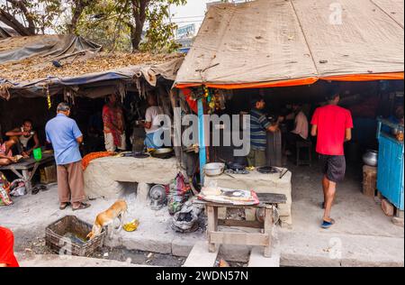 Die Einheimischen treffen sich in einem typischen Straßencafé, das Street Food in der Strand Bank Road, Kalkutta, Westbengalen, Indien, kocht Stockfoto