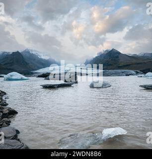 Gletscherzungenrutschen von der Vatnajokull-Eiskappe oder dem Vatna-Gletscher in der Nähe des subglazialen Vulkans Oraefajokull, Island. Gletscherlagune mit Eisblöcken und Surro Stockfoto