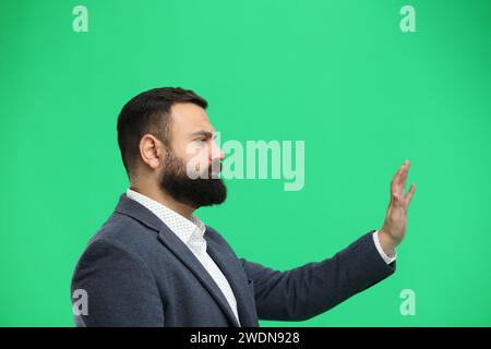Ein Mann aus der Nähe, auf grünem Hintergrund, der mit der Hand winkt Stockfoto