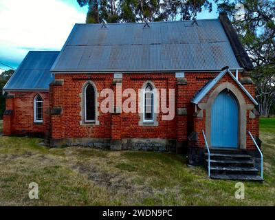 Ein rotes Backsteinhaus mit einer leuchtenden blauen Tür auf einem üppig grünen Rasen Stockfoto