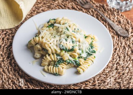 Fusilli Pasta mit Spinat und Ricotta garniert mit geriebenem Parmesan Käse auf weißem Teller Stockfoto