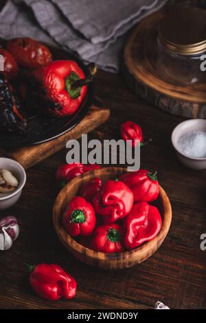 Schüssel mit roten Habanero-Paprika, verkohlten Tomaten und Glockenpfeffer für die Zubereitung von heißer Tomatensauce Stockfoto