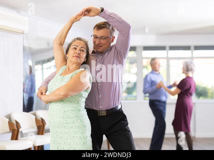 Mann mittleren Alters und ältere Frau tanzen klassische Walzer-Version zu zweit. Stockfoto