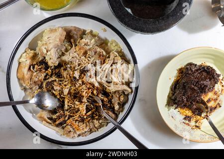 Kochen und Verarbeiten von Pulled Schweinefleisch mit roter Anchochili-Paste und Schweinefleisch auf einem Schneidebrett aus weißem Marmor Stockfoto