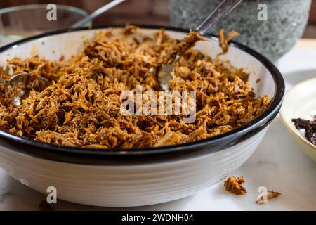 Kochen und Verarbeiten von Pulled Schweinefleisch mit roter Anchochili-Paste und Schweinefleisch auf einem Schneidebrett aus weißem Marmor Stockfoto