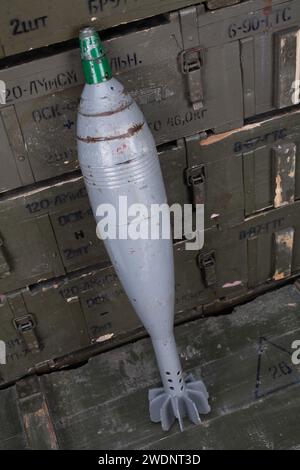 120 mm Mörserschale auf grüner Armeekiste. Text auf russisch - Art der Munition, Geschosskaliber, Geschossart, Stückzahl und Gewicht. Stockfoto