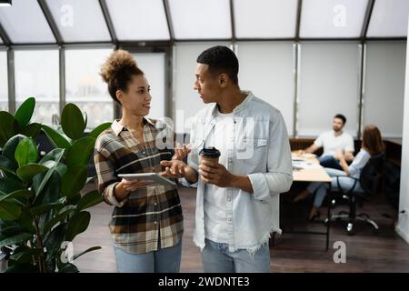 Gruppe verschiedener Geschäftsleute, die ein Notebook nutzen, während sie gemeinsam an einem modernen Arbeitsplatz arbeiten. Stockfoto