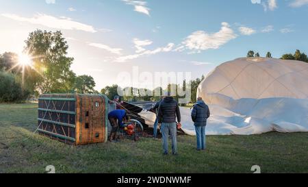 Am frühen Morgen, wenn die Sonne aufgeht, bereitet ein zusammengeschlossenes Team einen Heißluftballon für den Flug vor. Stockfoto