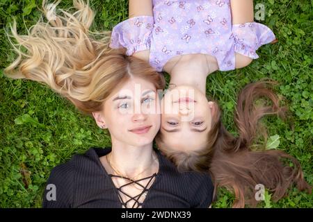 Mutter und Tochter umarmen sich auf Gras. Stockfoto