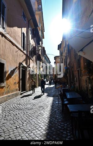 Die Sonne scheint, als die Menschen eine kleine Straße in Trastevere hinunterlaufen – Rom, Italien – 1. November 2022 Stockfoto